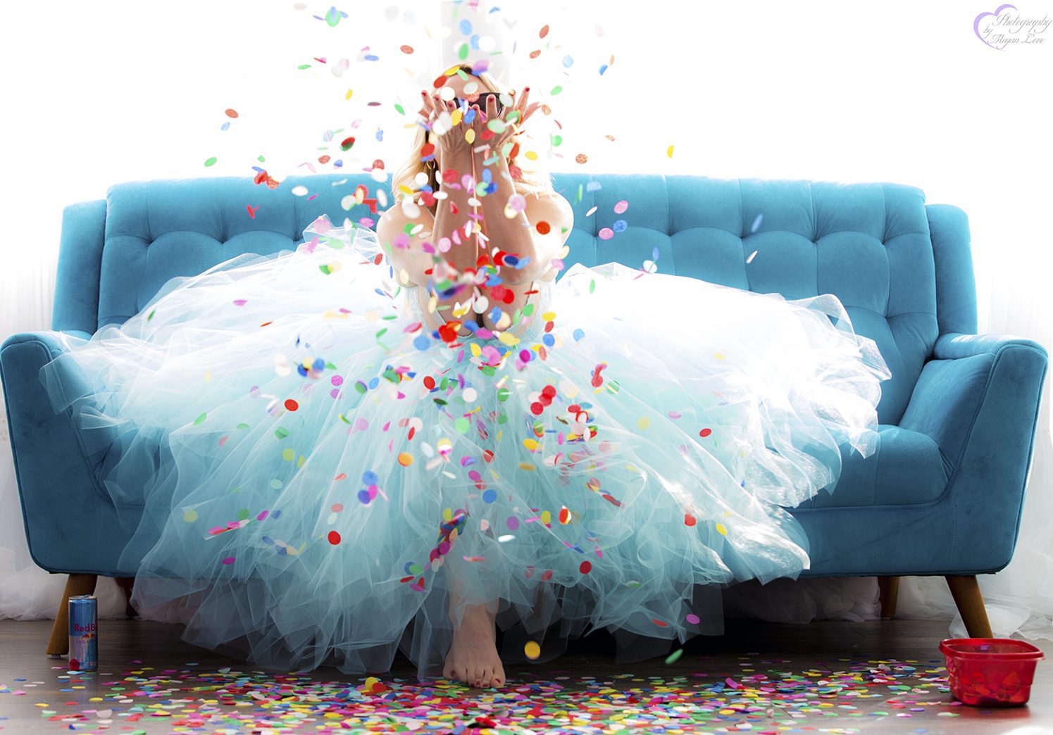 Megan Love sitting on blue couch wearing a tutu and throwing confetti